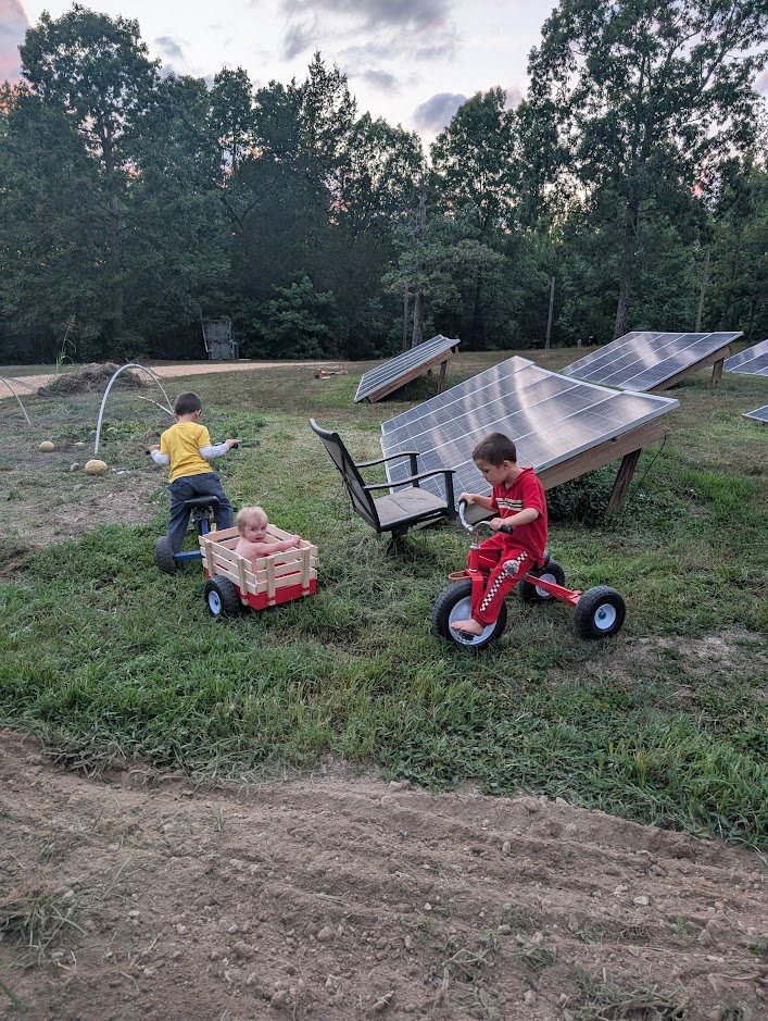 Children riding trikes in front of solar panels