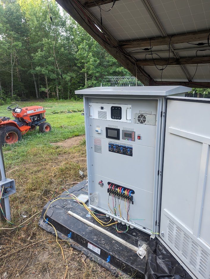 Cabinet outdoors under a solar array with a tractor nearby