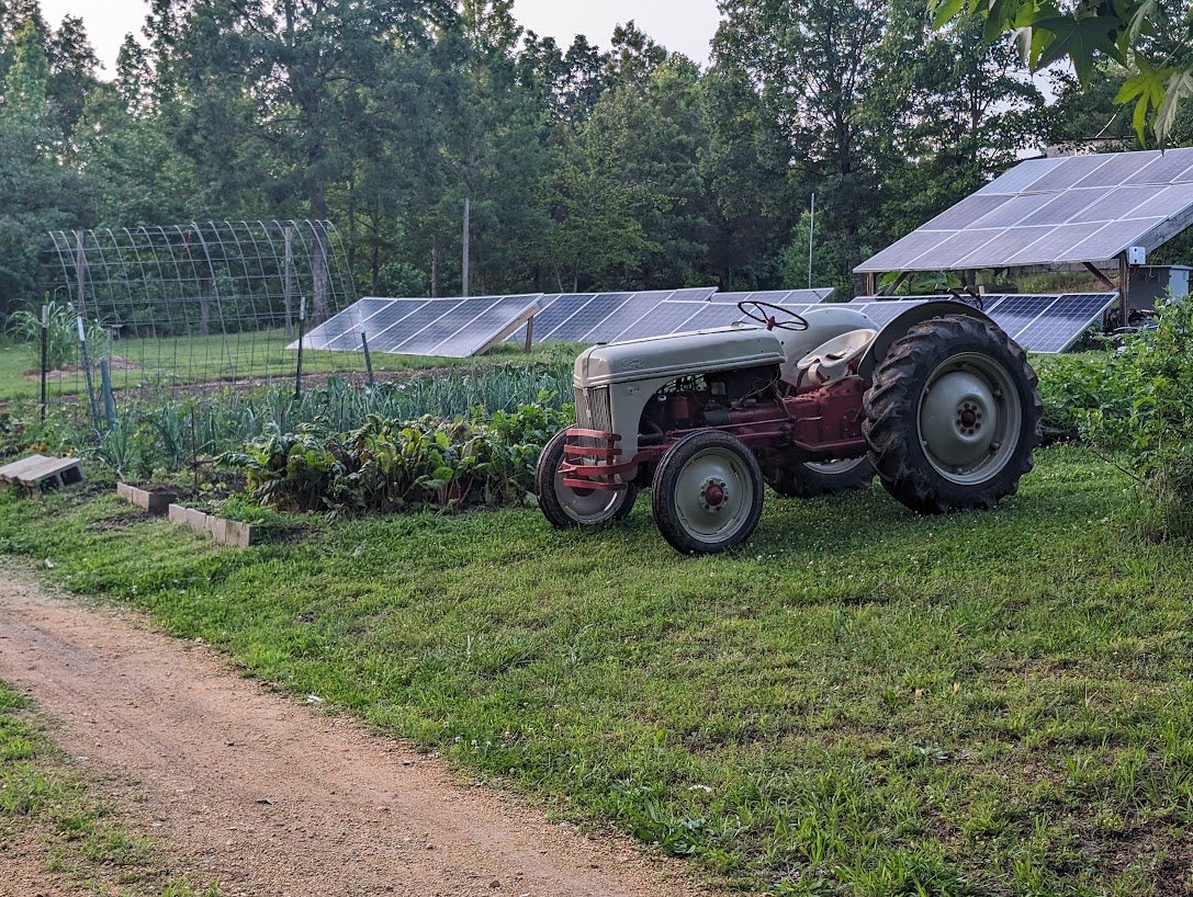Vintage tractor in front of ground-mount solar arrays